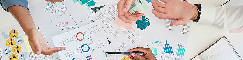 AdobeStock_542873161 Hände über Blättern mit einer Darstellung einer Wirkungsanalyse von Werbekampagnen